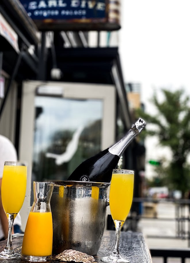 a bottle of champagne and mimosas on a table outside